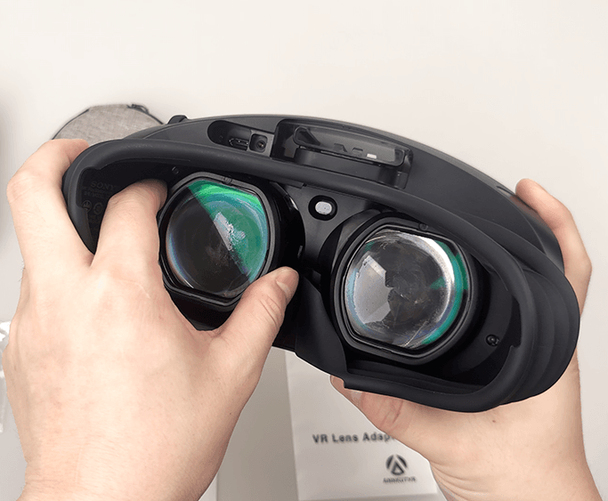 Front view of a PSVR2 headset with prescription lens inserts mounted over the optics, showing secure clip-on fit