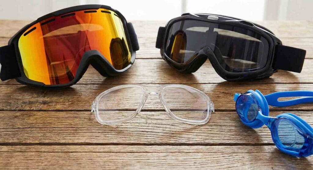 Prescription goggle inserts placed on a table with different types of goggles