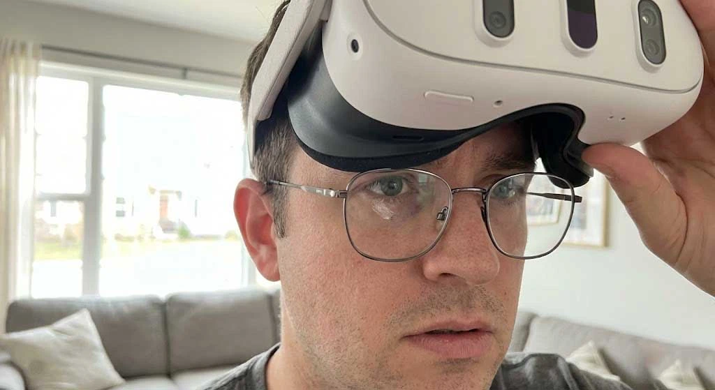 Is It Safe to Wear Glasses Inside Meta Quest 3? Read This Before You Play 1 A close-up photograph of a user lifting their Meta Quest 3 headset, revealing metal-framed glasses resting dangerously close to the internal pancake lenses, illustrating the risk of scratching the VR optics.