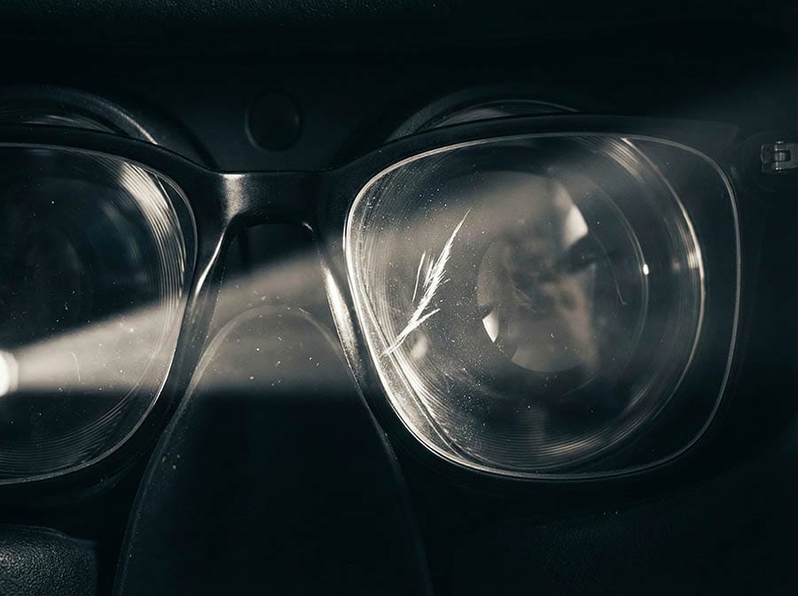Close-up shot inside a PSVR2 headset showing the risk of permanent lens scratches caused by friction between thick-rimmed glasses and the VR Fresnel lenses.
